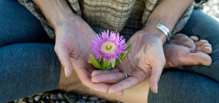 Woman holding a flower in her hands by Elena Ray